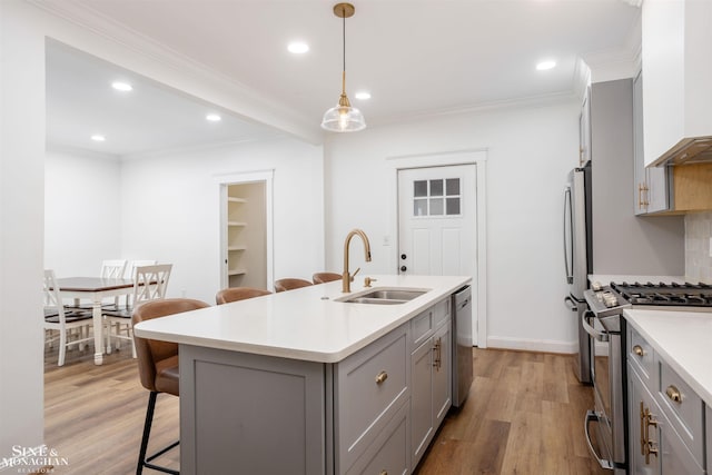 kitchen with gray cabinets, sink, appliances with stainless steel finishes, and an island with sink