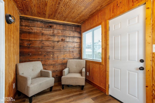 sitting room with hardwood / wood-style flooring, wood walls, and wood ceiling