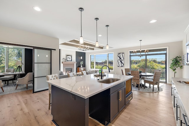 kitchen featuring white cabinetry, sink, hanging light fixtures, and an island with sink