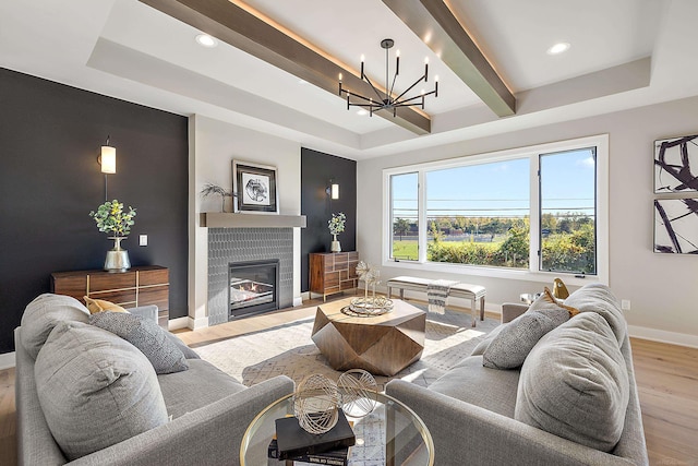 living room featuring a raised ceiling, light wood-type flooring, and a chandelier