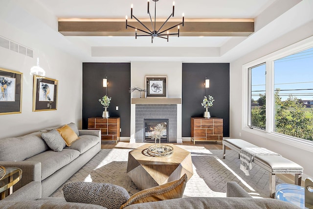 living room featuring a fireplace, hardwood / wood-style floors, a chandelier, and a tray ceiling