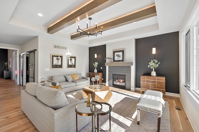 living room with a tray ceiling, light hardwood / wood-style flooring, and a notable chandelier