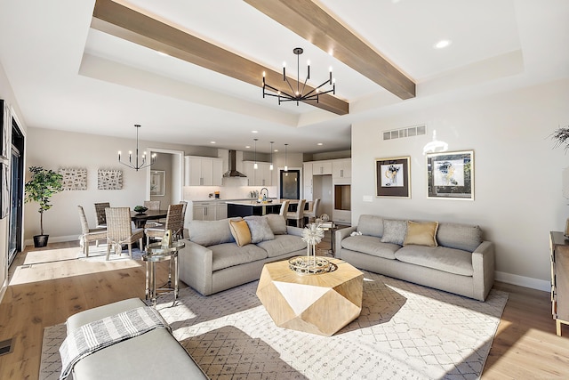 living room featuring sink, light hardwood / wood-style flooring, and an inviting chandelier