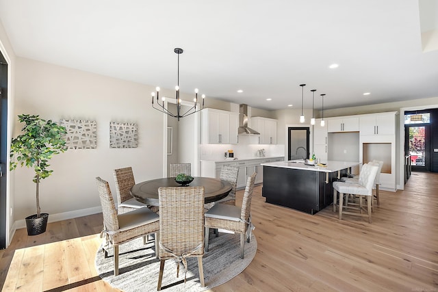 dining area with light hardwood / wood-style flooring, a chandelier, and sink