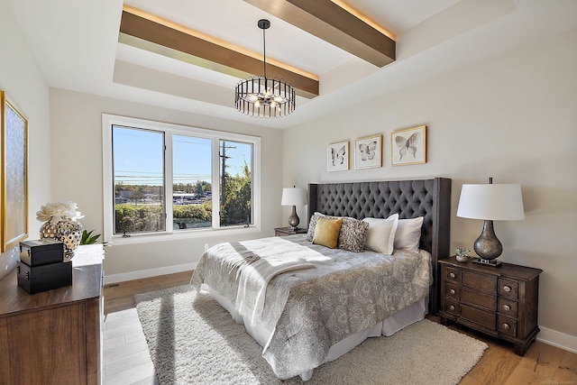 bedroom featuring light hardwood / wood-style flooring, beamed ceiling, and a notable chandelier