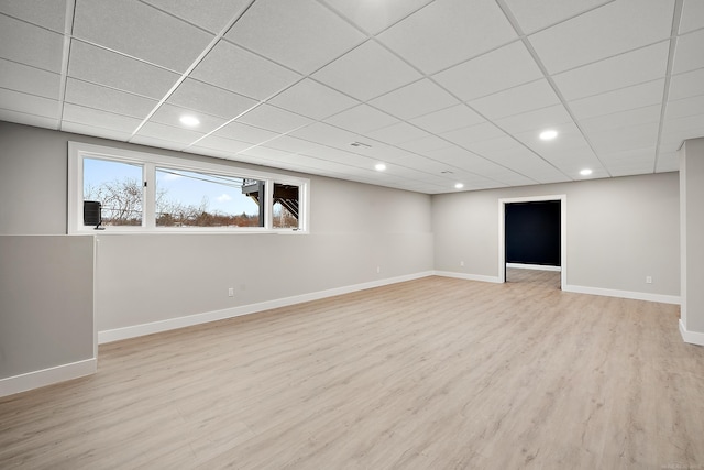 basement with a paneled ceiling and light wood-type flooring