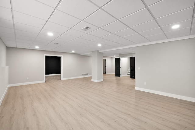 basement with a drop ceiling and light hardwood / wood-style flooring