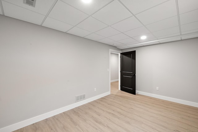 empty room with a drop ceiling and light wood-type flooring