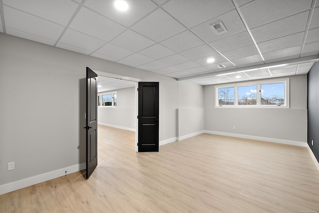 basement featuring a drop ceiling and light hardwood / wood-style floors