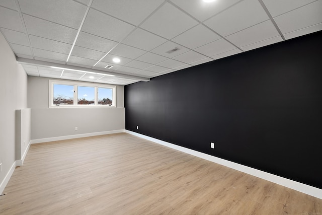 empty room featuring a drop ceiling and light hardwood / wood-style floors