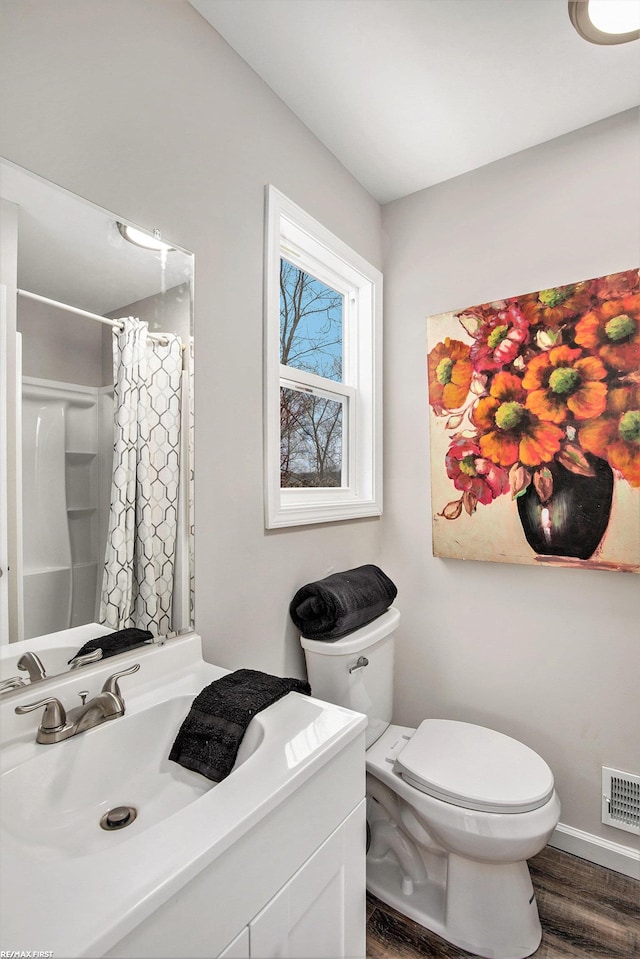 bathroom featuring hardwood / wood-style floors, vanity, toilet, and walk in shower