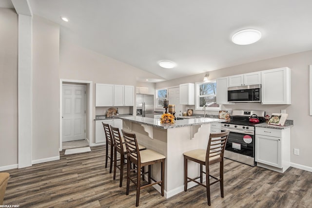 kitchen featuring a center island, light stone counters, white cabinetry, and appliances with stainless steel finishes