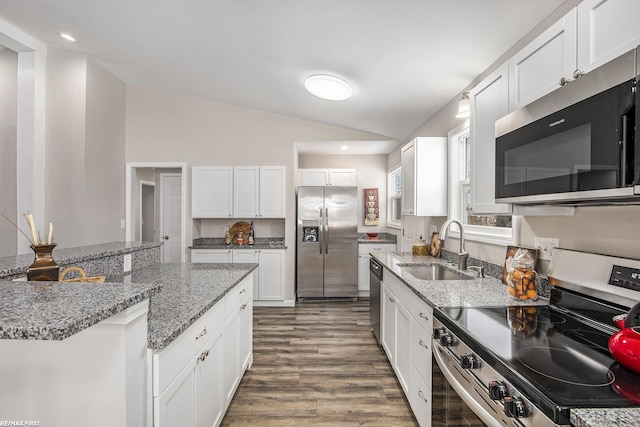 kitchen with white cabinets, appliances with stainless steel finishes, vaulted ceiling, and sink