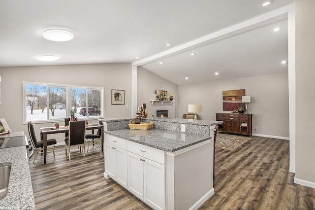 kitchen featuring white cabinetry, a center island, vaulted ceiling with beams, light stone counters, and dark hardwood / wood-style flooring