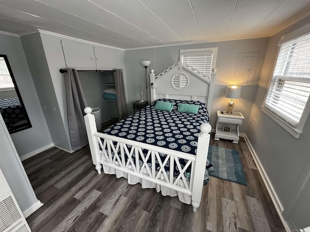 bedroom featuring wood finished floors, crown molding, and baseboards