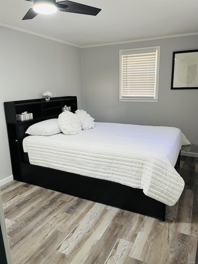 bedroom with hardwood / wood-style floors, ceiling fan, and ornamental molding