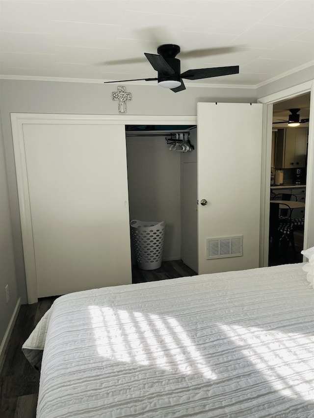 bedroom featuring ceiling fan, a closet, dark wood-type flooring, and ornamental molding