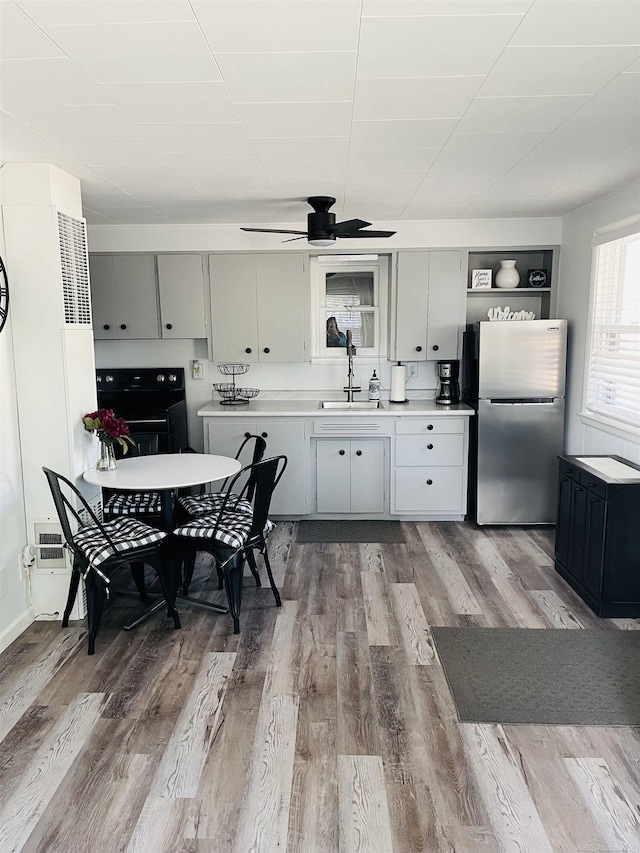 kitchen featuring stainless steel refrigerator, ceiling fan, sink, gray cabinetry, and hardwood / wood-style flooring