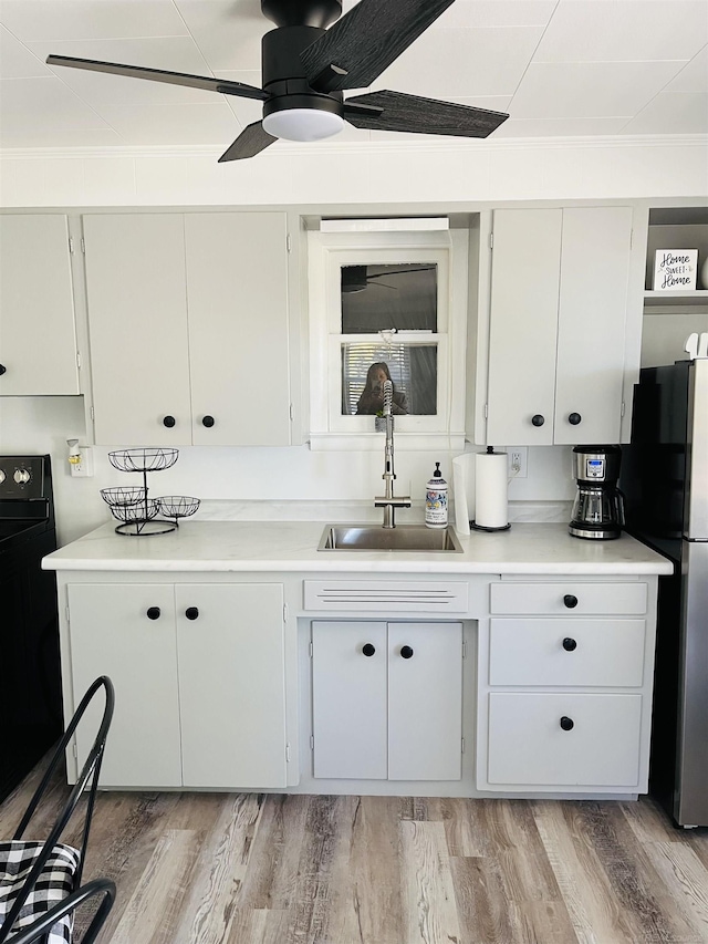 kitchen with white cabinets, ceiling fan, and sink