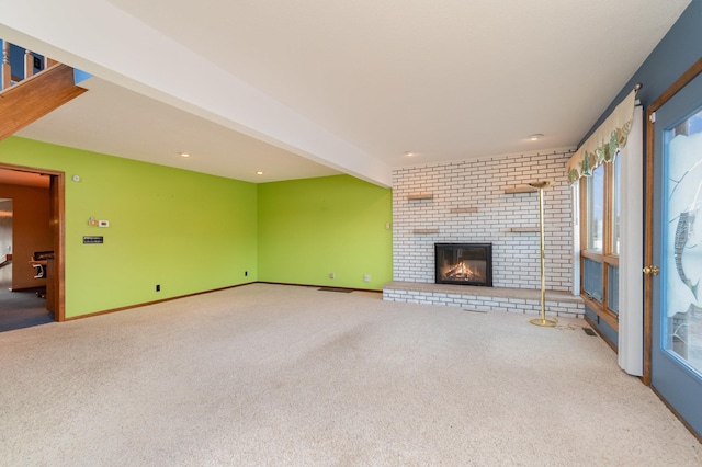 unfurnished living room with a fireplace, beam ceiling, and carpet floors