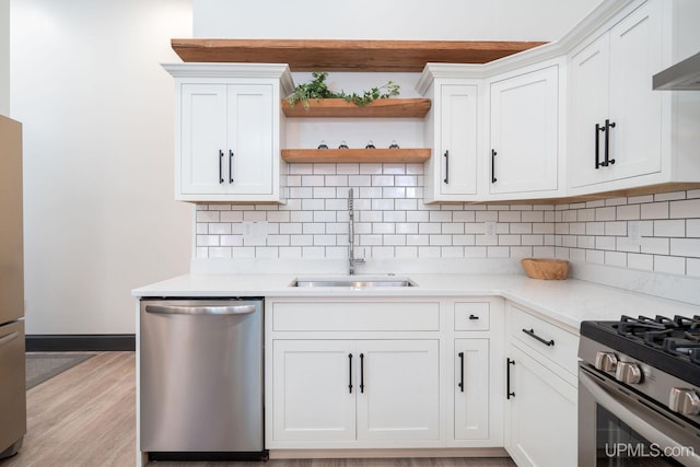 kitchen with white cabinets, sink, light stone countertops, light hardwood / wood-style floors, and stainless steel appliances