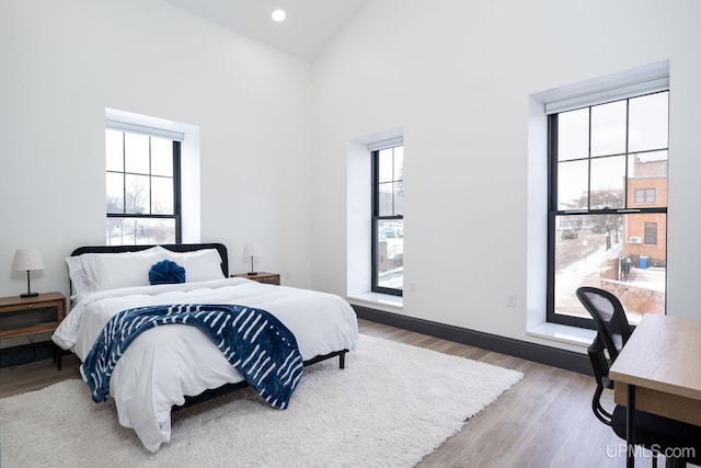 bedroom featuring hardwood / wood-style floors, high vaulted ceiling, and multiple windows