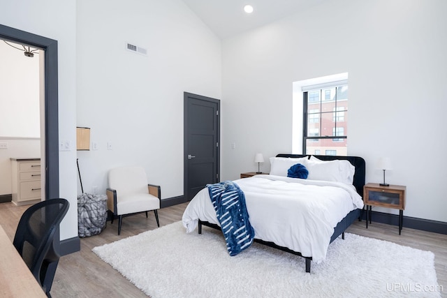 bedroom featuring high vaulted ceiling and light wood-type flooring