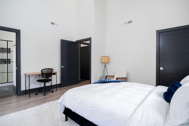 bedroom with hardwood / wood-style floors and a towering ceiling