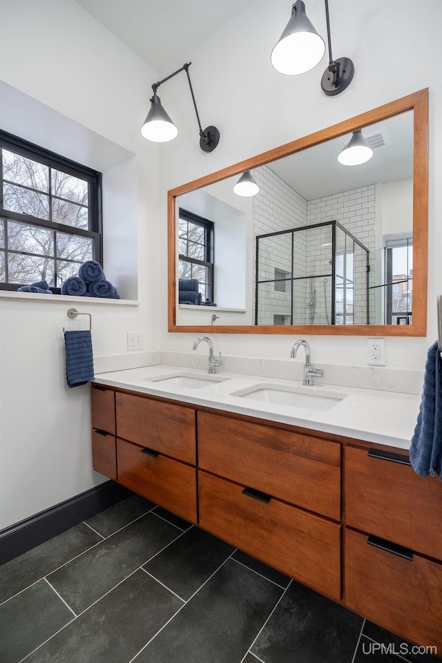 bathroom with tile patterned floors, plenty of natural light, walk in shower, and vanity