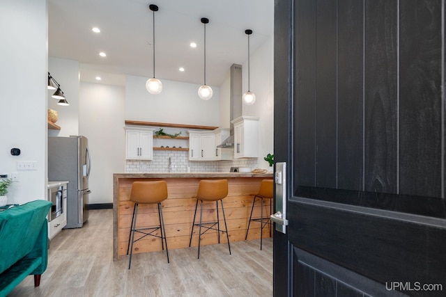 kitchen with white cabinets, tasteful backsplash, light hardwood / wood-style floors, kitchen peninsula, and a breakfast bar area