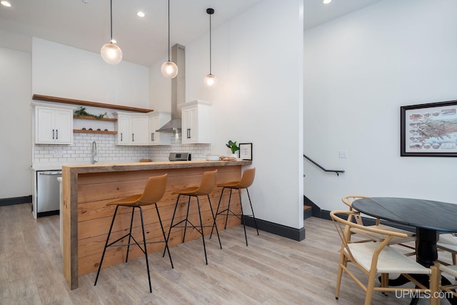 kitchen featuring kitchen peninsula, a kitchen breakfast bar, appliances with stainless steel finishes, decorative light fixtures, and white cabinetry