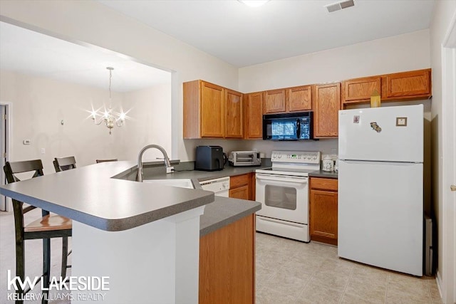 kitchen with white appliances, a breakfast bar, kitchen peninsula, and pendant lighting