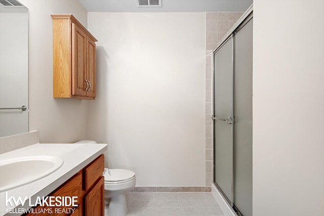 bathroom featuring toilet, vanity, and a shower with shower door