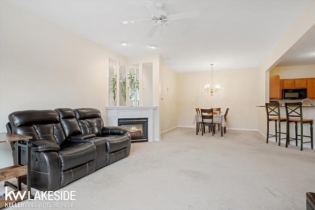 carpeted living room with ceiling fan with notable chandelier