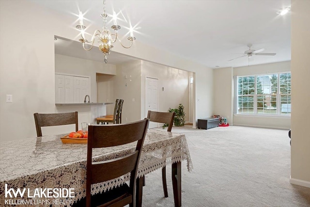 dining area with ceiling fan with notable chandelier and carpet floors