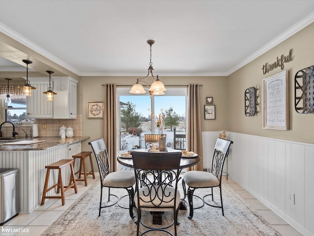 dining area featuring sink, light tile patterned floors, crown molding, and a notable chandelier