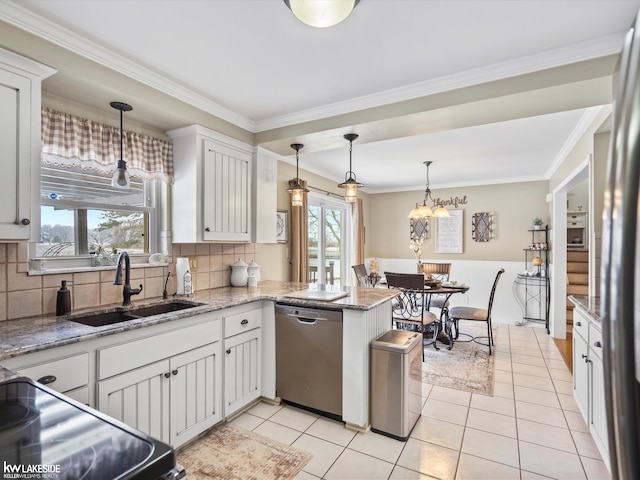 kitchen with appliances with stainless steel finishes, decorative light fixtures, white cabinetry, sink, and kitchen peninsula