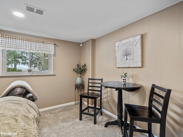 carpeted dining space with wood walls