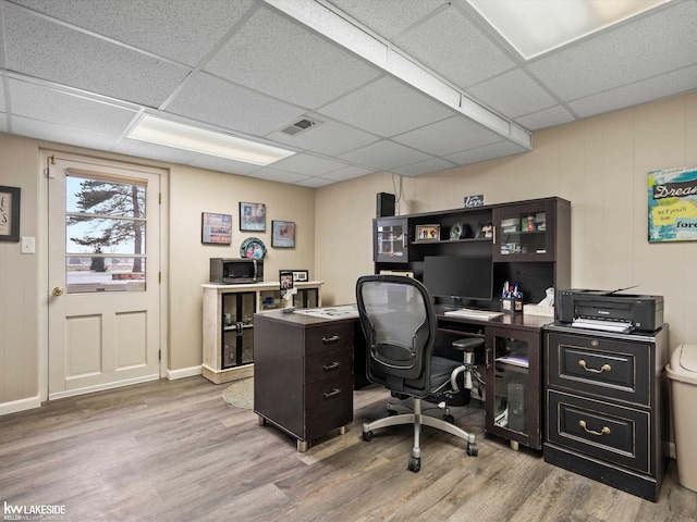 office area with light hardwood / wood-style floors and a drop ceiling