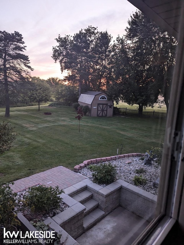 yard at dusk featuring a patio area and a storage shed