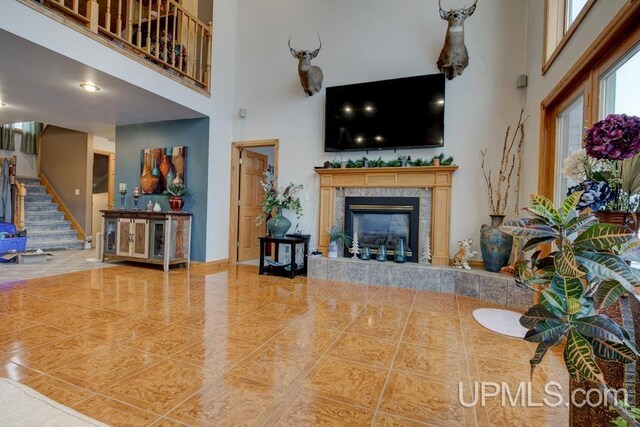 tiled living room featuring a towering ceiling and a fireplace