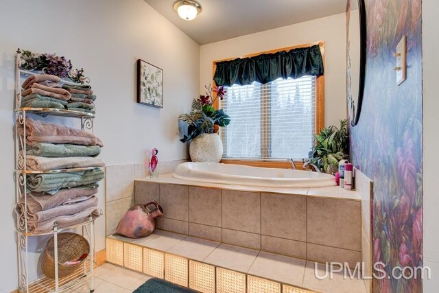 bathroom with a relaxing tiled tub and tile patterned flooring