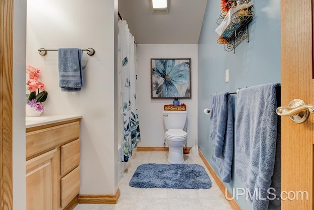 bathroom featuring toilet, vanity, tile patterned floors, and curtained shower