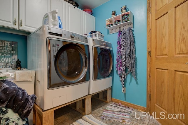 clothes washing area with cabinets and washer and clothes dryer