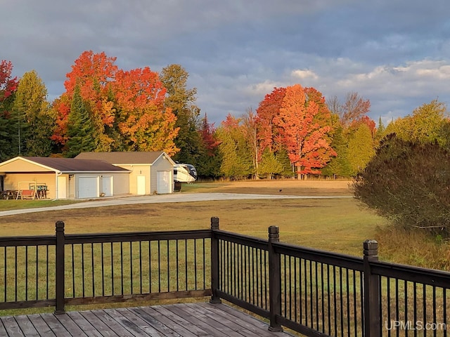 wooden deck featuring a lawn, an outbuilding, and a garage