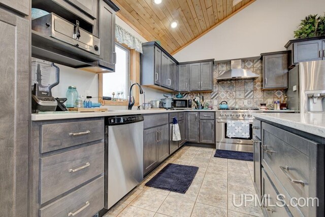 kitchen with vaulted ceiling, wall chimney exhaust hood, tasteful backsplash, wood ceiling, and appliances with stainless steel finishes