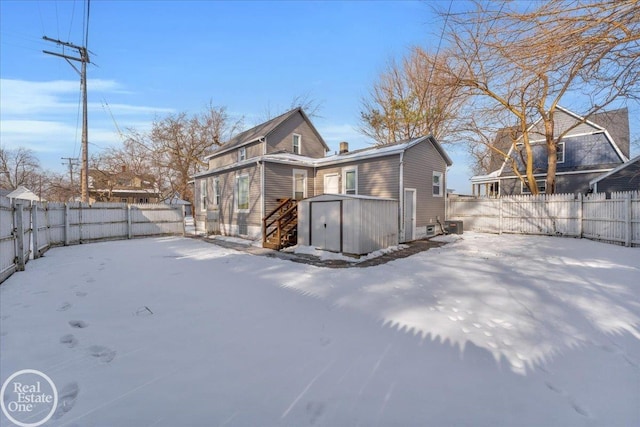 snow covered rear of property with a storage unit