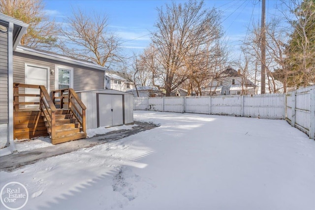 snowy yard featuring a storage unit