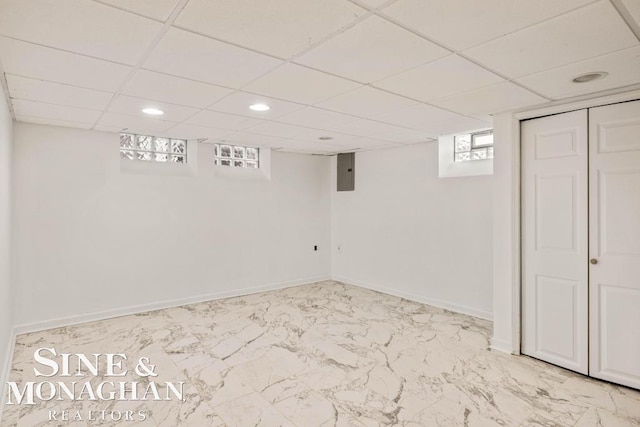 basement with electric panel and a drop ceiling