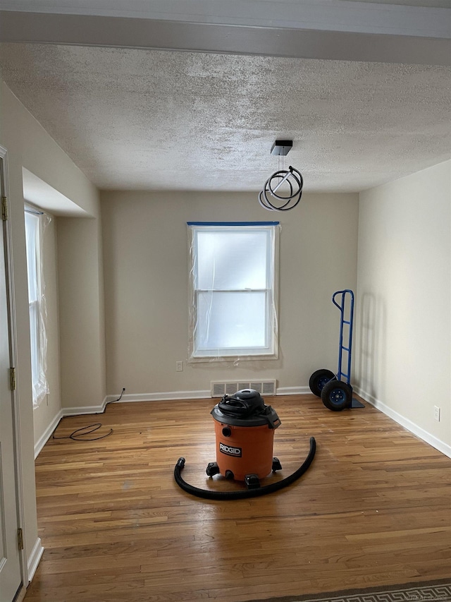 interior space with a textured ceiling and hardwood / wood-style flooring